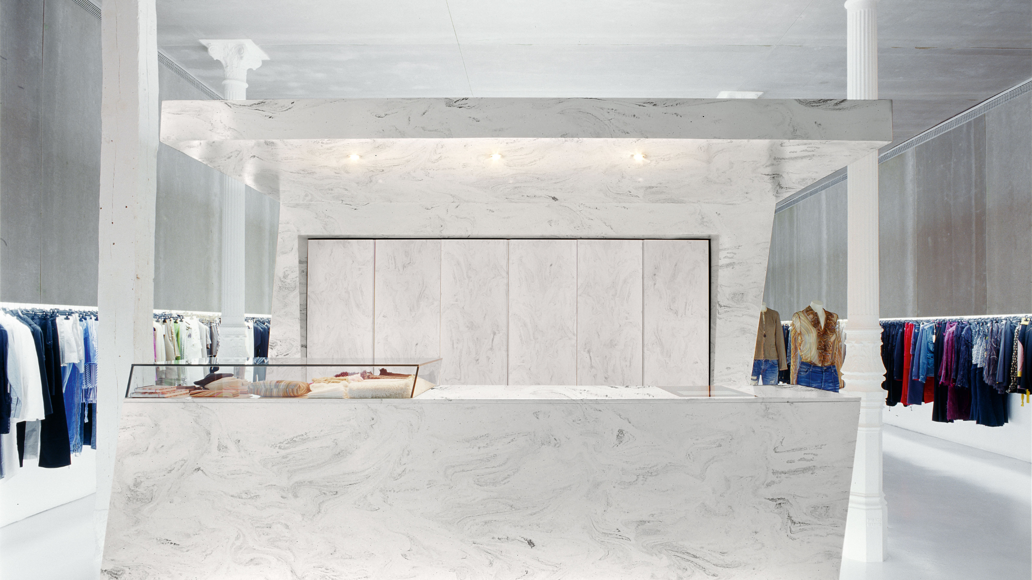 Aplikacja materiału Corian Solid surface w sektorze Retail - Limestone Prima - lada sprzedażowa w eleganckim sklepie, butiku